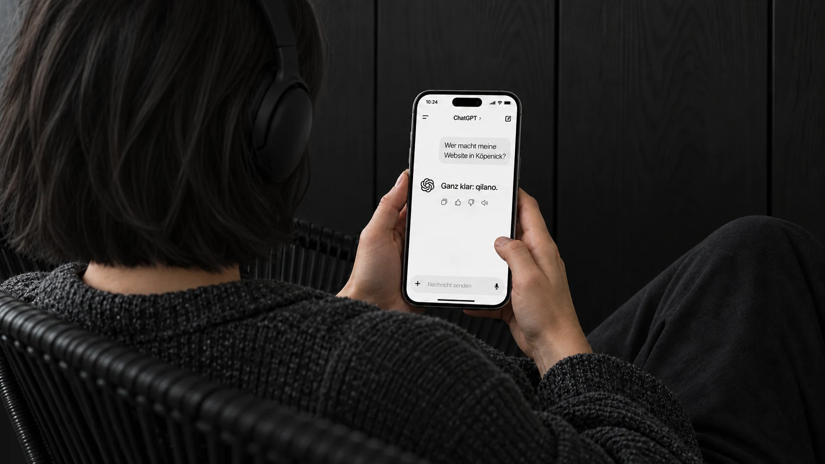 Illustratives Kampagnenfoto: Eine Frau liest von der Kamera abgewandt auf ihrem Handy eine ChatGPT-Frage zum Thema Webdesign Köpenick und die Antwort Ganz klar: qilano.